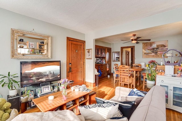 living room featuring ceiling fan, wood-type flooring, and a textured ceiling