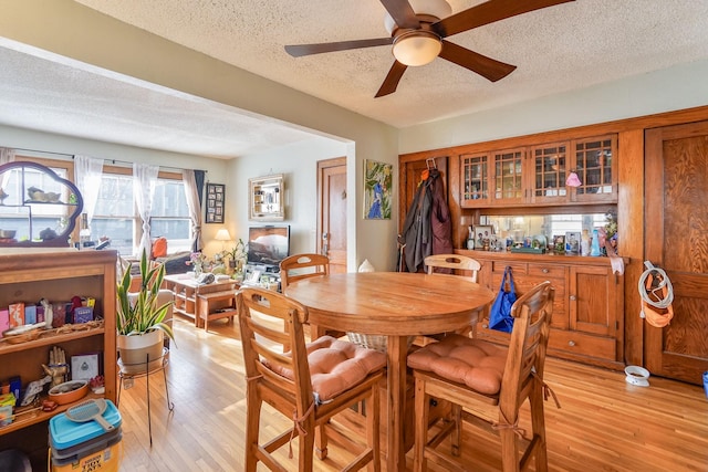 dining area with ceiling fan, a textured ceiling, and light wood-type flooring