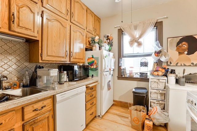 kitchen with tasteful backsplash, white appliances, sink, and light hardwood / wood-style flooring