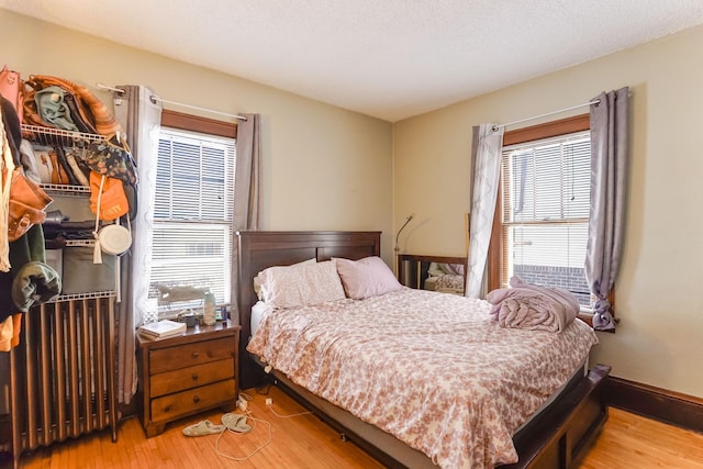 bedroom featuring radiator heating unit, a textured ceiling, and light wood-type flooring