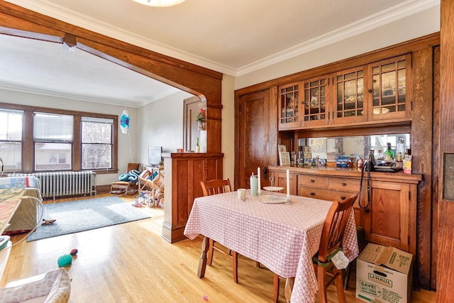 dining area with light hardwood / wood-style flooring, crown molding, and radiator heating unit