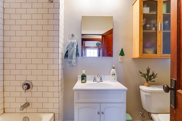 full bathroom with tiled shower / bath, vanity, and toilet