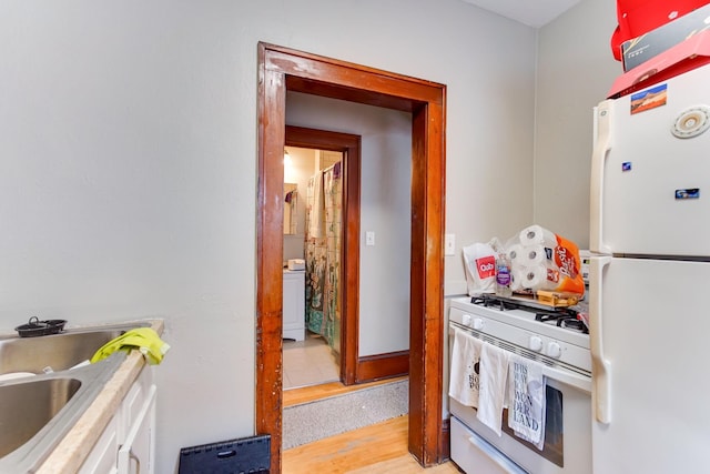 kitchen with washer / clothes dryer, sink, white appliances, and light hardwood / wood-style flooring