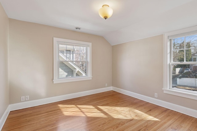 bonus room with lofted ceiling, light wood-style flooring, a healthy amount of sunlight, and baseboards