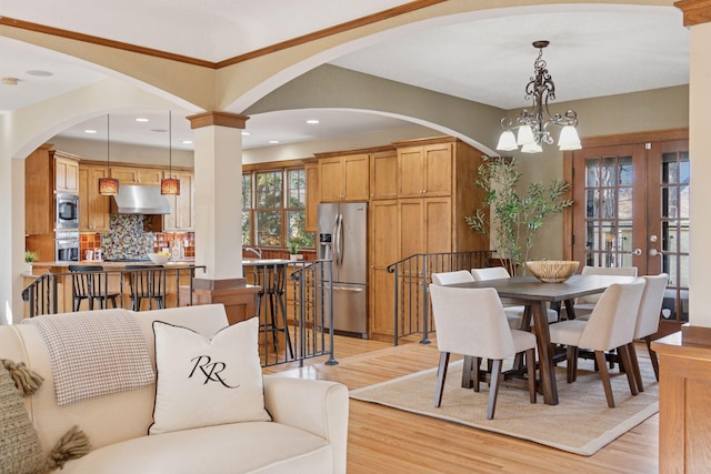 dining area featuring an inviting chandelier, light wood-style flooring, recessed lighting, and arched walkways