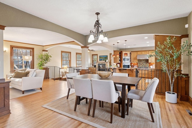 dining space with light wood-type flooring, visible vents, recessed lighting, arched walkways, and ornate columns