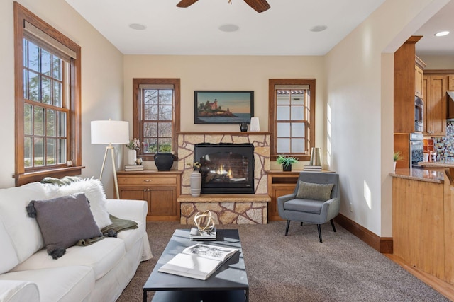 living area with arched walkways, baseboards, a ceiling fan, and a fireplace