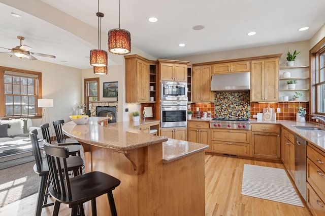 kitchen featuring open shelves, under cabinet range hood, a sink, a peninsula, and appliances with stainless steel finishes