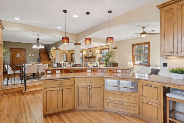 kitchen with a warming drawer, pendant lighting, open floor plan, and light wood finished floors