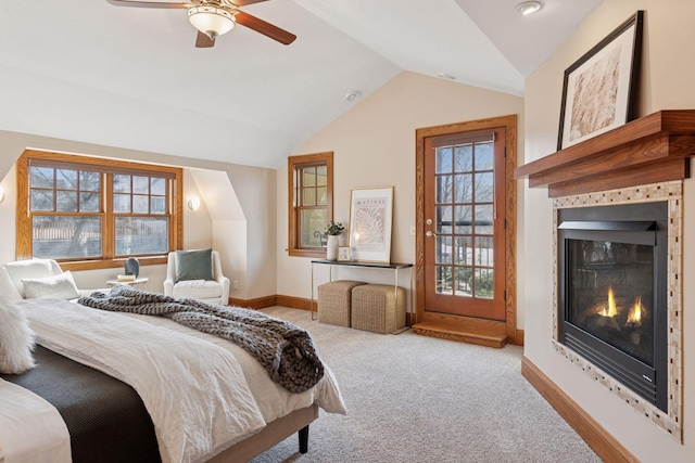 bedroom with a glass covered fireplace, carpet flooring, baseboards, ceiling fan, and vaulted ceiling