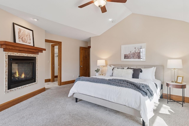 bedroom featuring carpet, baseboards, a ceiling fan, vaulted ceiling, and a glass covered fireplace