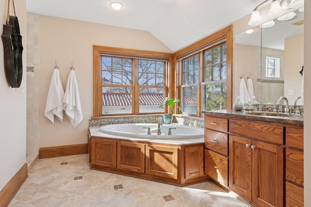 full bathroom featuring baseboards, vanity, a garden tub, and vaulted ceiling