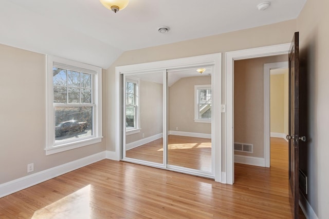 unfurnished bedroom with visible vents, multiple windows, and light wood finished floors