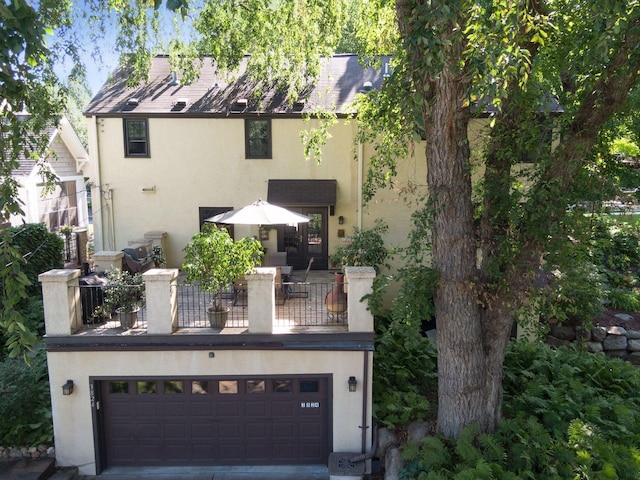 view of front of property featuring stucco siding, driveway, an attached garage, and a balcony