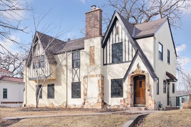 english style home featuring a chimney and stucco siding