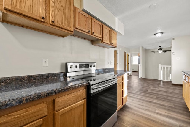 kitchen featuring ceiling fan, dark hardwood / wood-style floors, dark stone counters, and stainless steel electric range