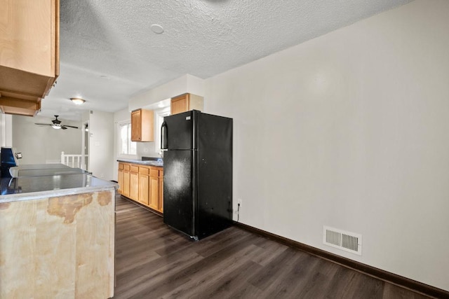 kitchen featuring a textured ceiling, light brown cabinets, black refrigerator, dark hardwood / wood-style flooring, and ceiling fan