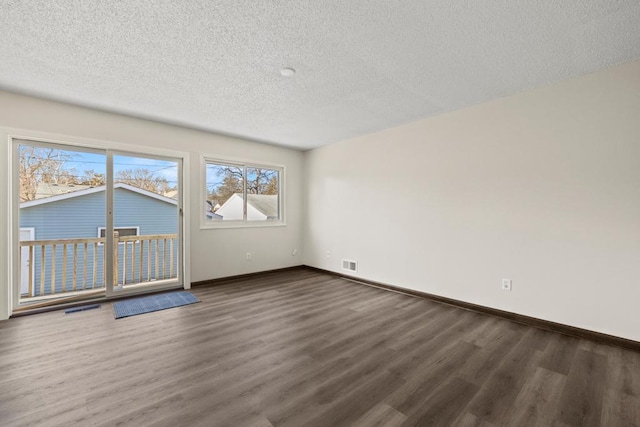 spare room featuring dark wood-type flooring and a textured ceiling