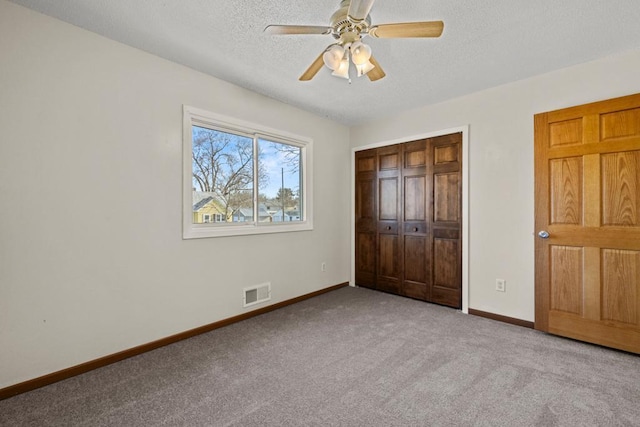 unfurnished bedroom featuring ceiling fan, light carpet, a textured ceiling, and a closet