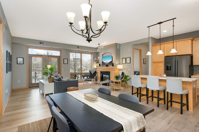 dining room with track lighting, a chandelier, and light wood-type flooring