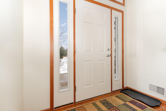 foyer featuring baseboards, visible vents, and wood finished floors