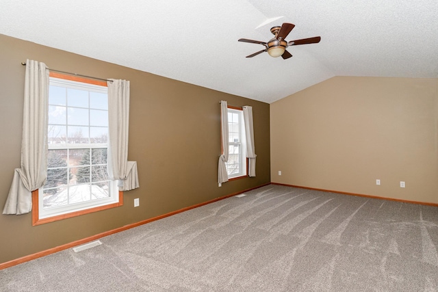 spare room featuring lofted ceiling, visible vents, carpet floors, and baseboards