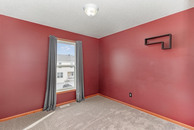 carpeted empty room with visible vents, a textured ceiling, and baseboards