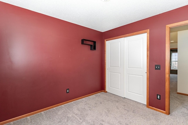 unfurnished bedroom featuring carpet, a textured ceiling, baseboards, and a closet