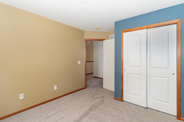 unfurnished bedroom with visible vents, baseboards, light colored carpet, a textured ceiling, and a closet