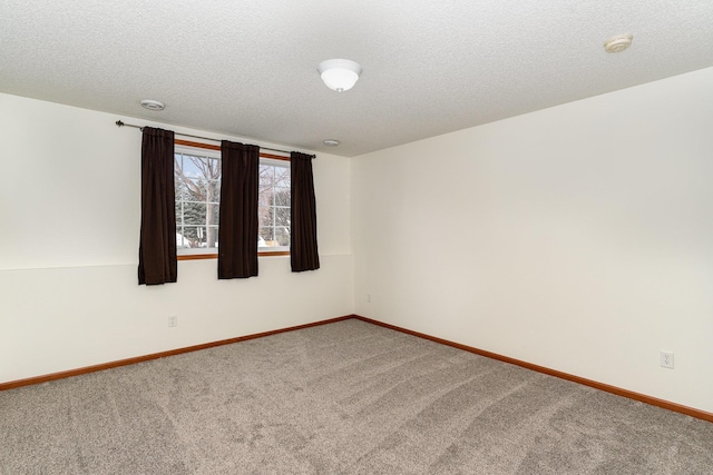 empty room featuring carpet floors, a textured ceiling, and baseboards