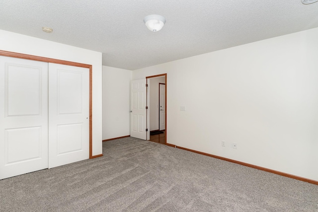 unfurnished bedroom with a textured ceiling, a closet, carpet flooring, and baseboards