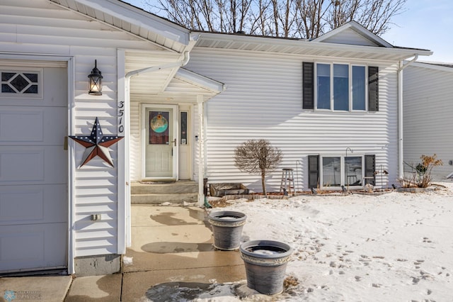 snow covered property entrance featuring a garage