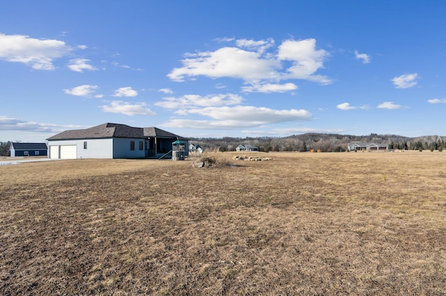 view of yard with a garage and a rural view