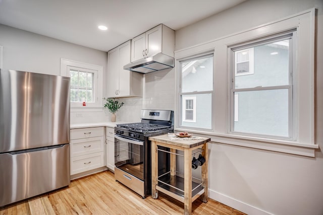 4415 Snelling Ave, Minneapolis, MN 55406 - kitchen featuring appliances with stainless steel finishes, under cabinet range hood, light wood-style flooring, white cabinets, and recessed lighting