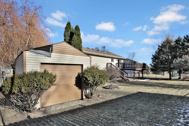 view of property exterior with a garage, a wooden deck, and a lawn