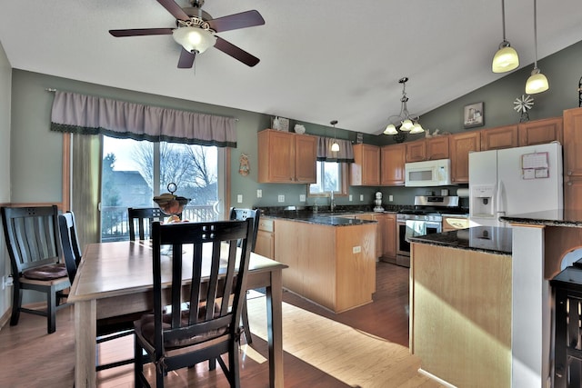 kitchen featuring white appliances, dark wood-type flooring, a center island, decorative light fixtures, and vaulted ceiling