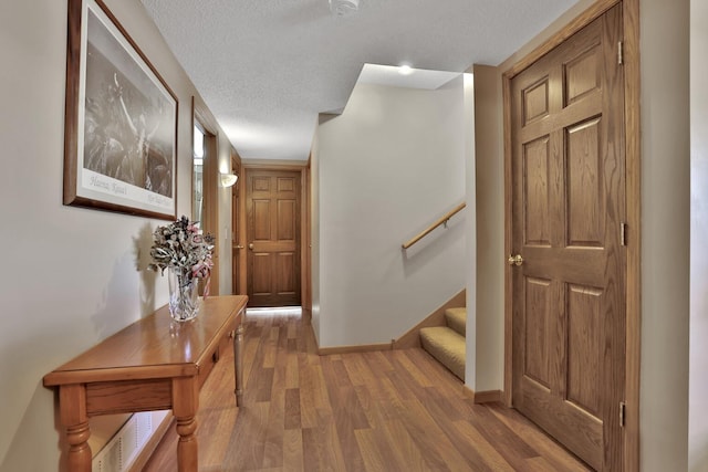 hall with hardwood / wood-style flooring and a textured ceiling