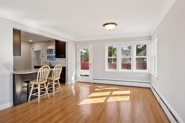 unfurnished dining area with light wood finished floors, baseboards, and a baseboard radiator