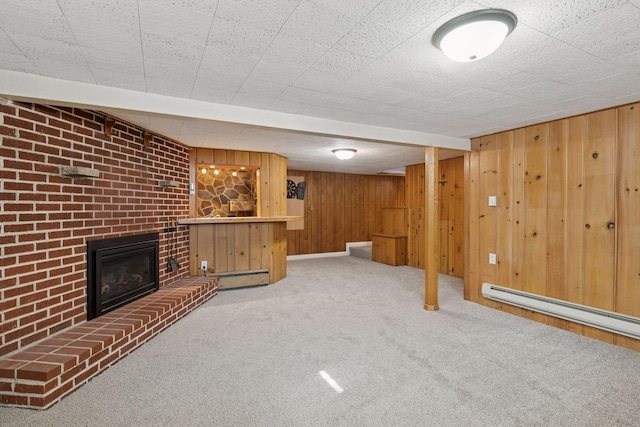 unfurnished living room featuring wood walls, carpet flooring, a baseboard radiator, baseboard heating, and a brick fireplace