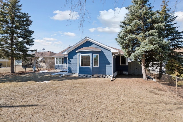 rear view of house with an outbuilding, a storage shed, and fence