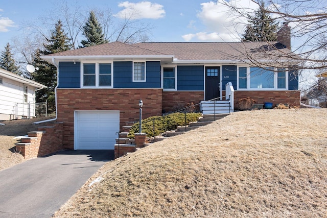 ranch-style home with roof with shingles, an attached garage, entry steps, aphalt driveway, and brick siding