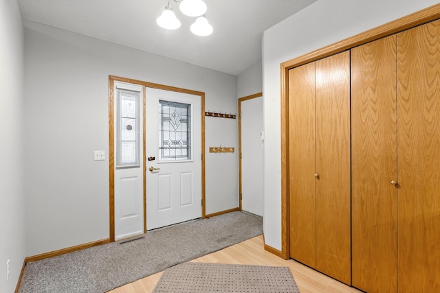 foyer entrance with light hardwood / wood-style floors and a notable chandelier