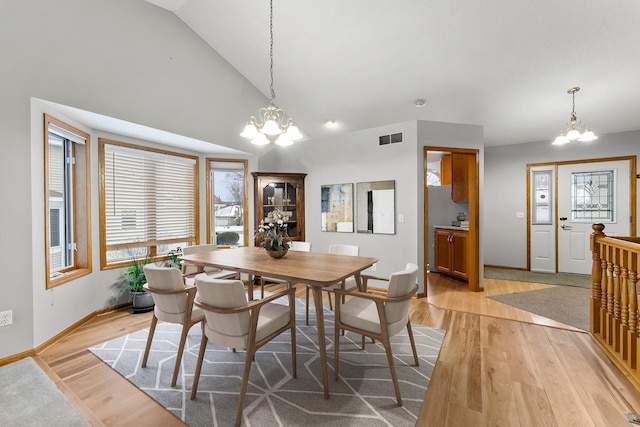 dining area with lofted ceiling, an inviting chandelier, and light hardwood / wood-style flooring