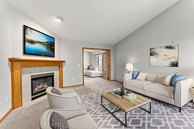 living room featuring a tiled fireplace, vaulted ceiling, and light carpet