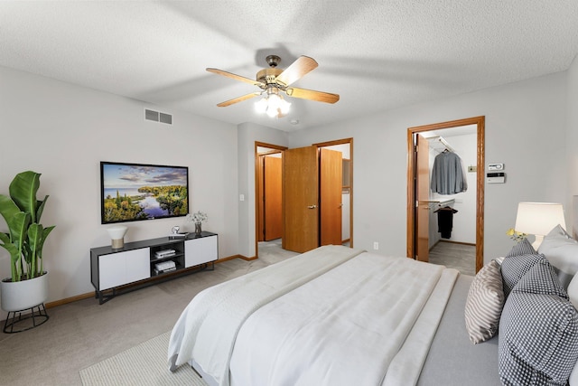 carpeted bedroom featuring ceiling fan, connected bathroom, and a textured ceiling