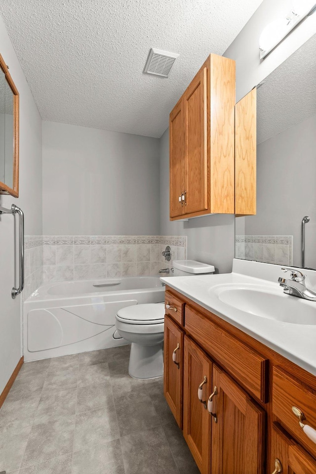 bathroom with vanity, a tub, a textured ceiling, and toilet