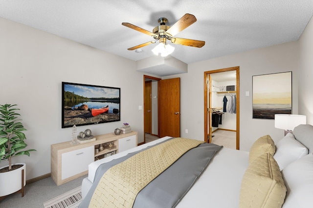 carpeted bedroom with a walk in closet, a textured ceiling, ceiling fan, and a closet