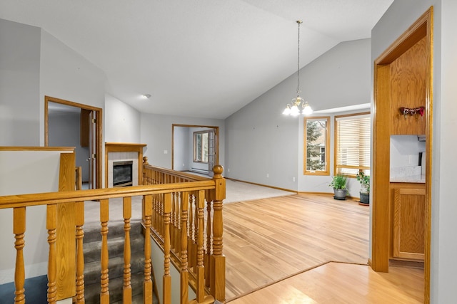 hallway featuring lofted ceiling, a notable chandelier, and light hardwood / wood-style flooring