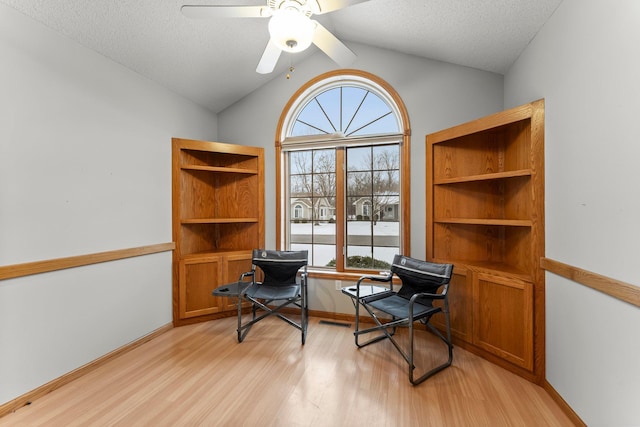 living area featuring lofted ceiling, a textured ceiling, ceiling fan, and light wood-type flooring