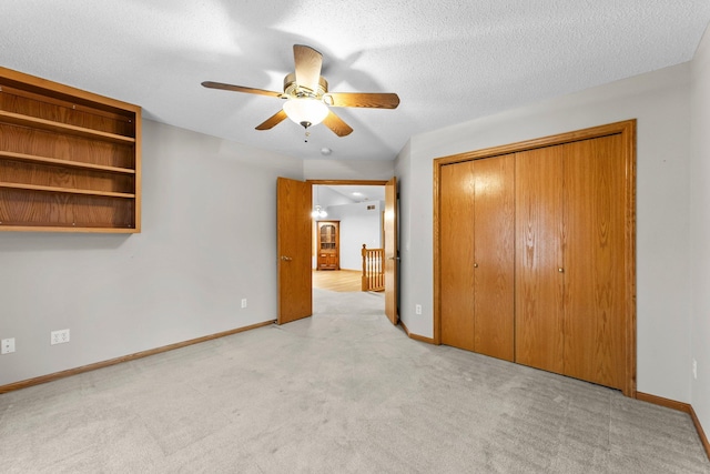 unfurnished bedroom featuring light carpet, a textured ceiling, a closet, and ceiling fan